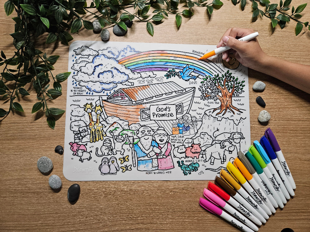DrawnBy: God's Promise Bible Story Coloring mat with illustrations and markers on a wooden table