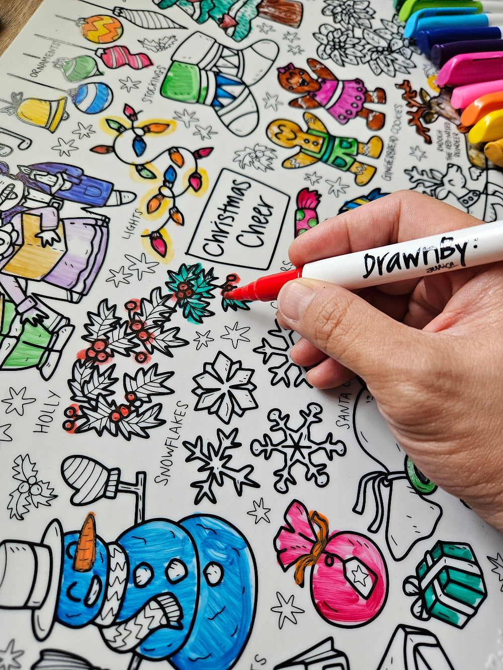 DrawnBy: Christmas Cheer Mat with Christmas-themed illustrations and a hand colouring it in with red marker