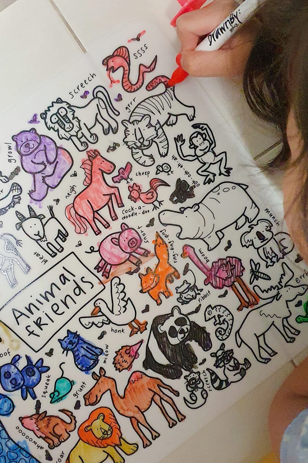 Child coloring animal illustrations on the DrawnBy: Animal Friends Colouring Mat